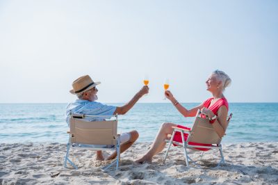 Senior couple relaxing and drink orange juice at tropical beach., Healthy seniors lifestyle concept.